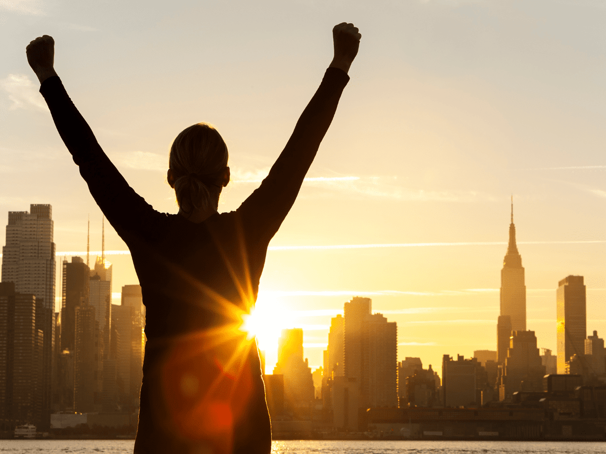 Person celebrating success at city sunrise