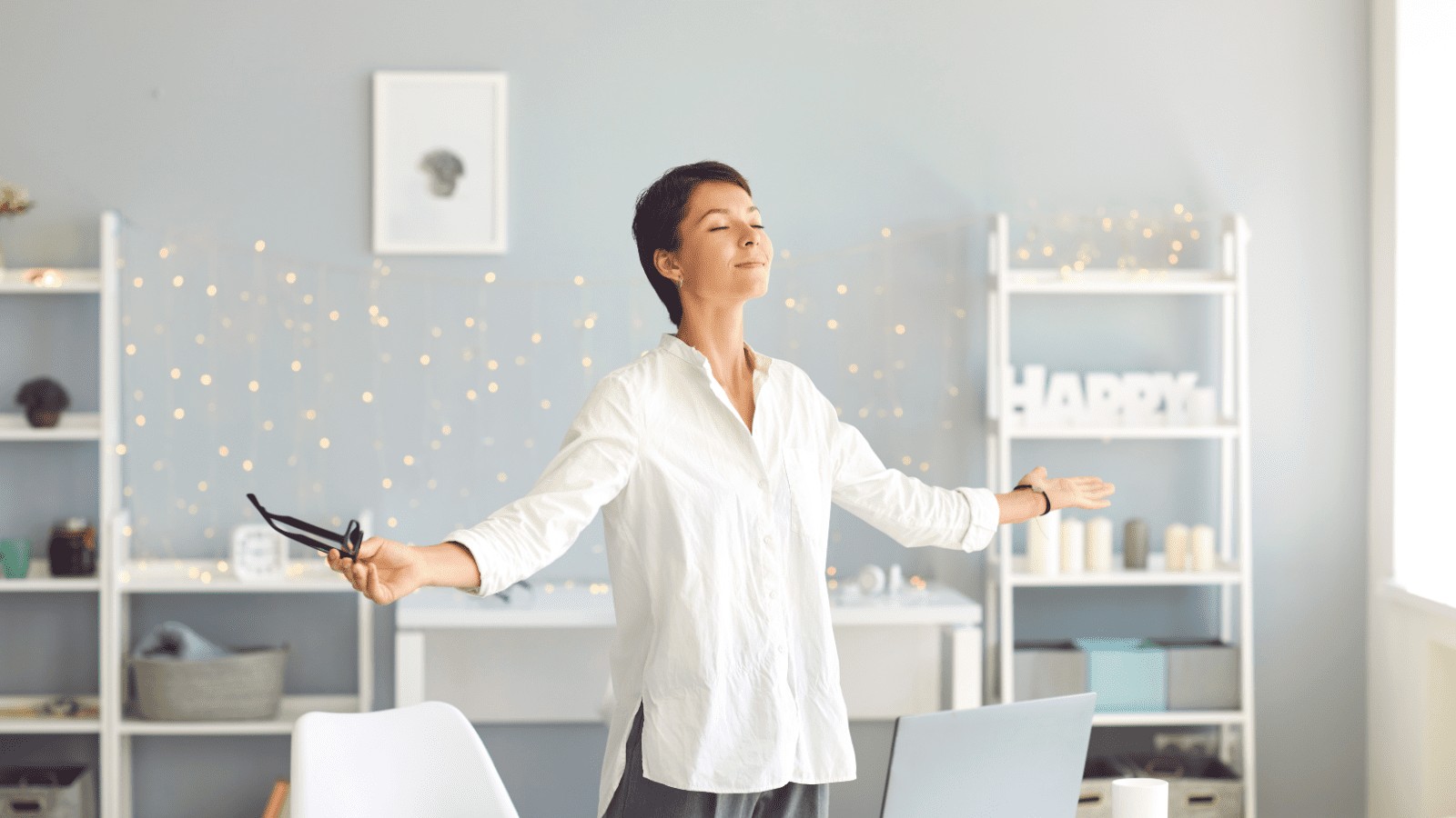 Woman relaxing with arms outstretched in home office.